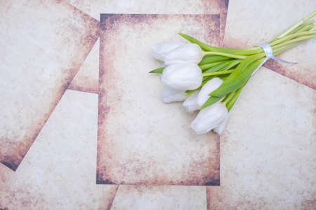 a bouquet of white tulips tied with a white ribbon lie on a vintage background, close-upの写真素材