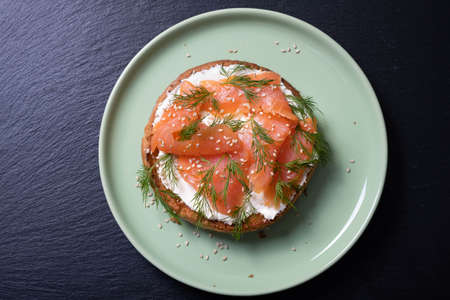 half a bun, oiled with fresh cream, garnished with smoked fish and sprinkled with fresh dill and...