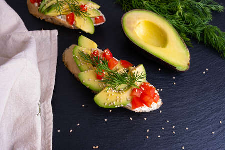 on a black background - half an avocado, dill and a napkin, canape - pieces of a crispy baguette...