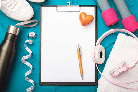 fitness at home - a bottle with water, a sheet of paper with a pen, dumbbells and measurement tape,...