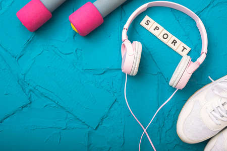 sport at home - white sneakers, dumbbells and headphones lie on a blue textured backgroundの写真素材