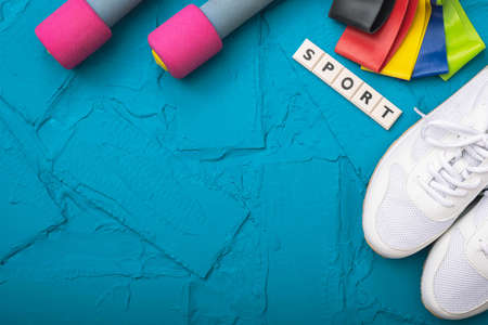 sports at home - white sneakers, dumbbells and rubber bands on a blue backgroundの写真素材