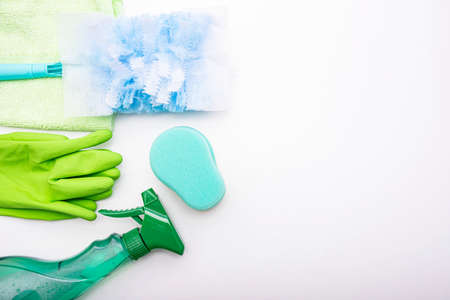 green gloves, window cleaning liquid, green sponge and dust brush lie on a white background