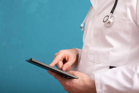 doctor holding tablet, close-up and blue background