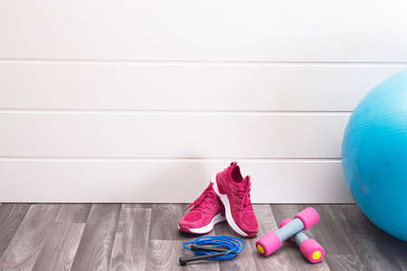 sports at home - pink sneakers, dumbbells, jump rope, ball on a white backgroundの写真素材
