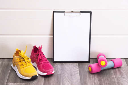 sports at home - pink and yellow sneakers, dumbbells and a note board close-upの写真素材