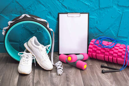 workout at home - white sneakers, dumbbells, jump rope, measurement tape, note board and massage...