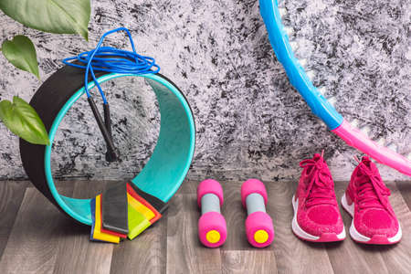 pink sneakers and dumbbells, massage roller, jump rope and rubber bands for training at homeの写真素材
