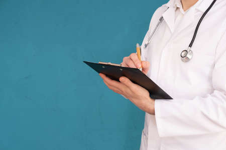 the doctor holds a folder in his hand and writes something on a blue background
