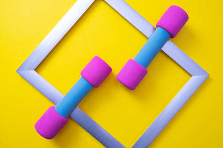 pink dumbbells and metal frame on yellow background, close-upの写真素材