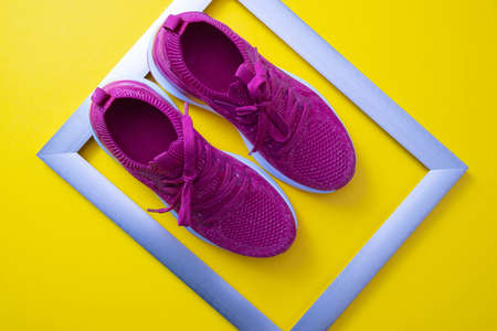 pink sneakers and metal frame on yellow background, close-upの写真素材