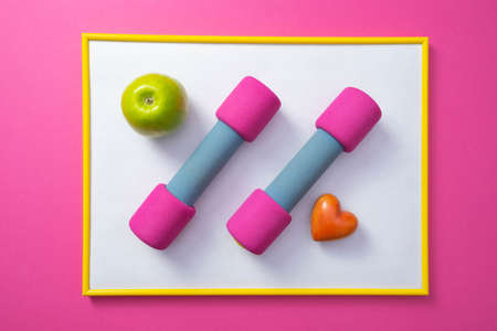 yellow frame with white background, pink dumbbells, green apple and heart, general pink backgroundの写真素材