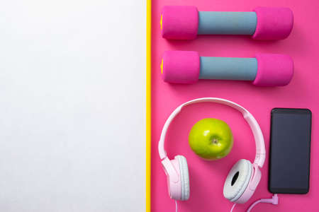 sports at home - dumbbells and cell phone with headphones, on a pink backgroundの写真素材