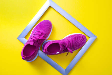 pink sneakers and metal frame on yellow background, close-upの写真素材