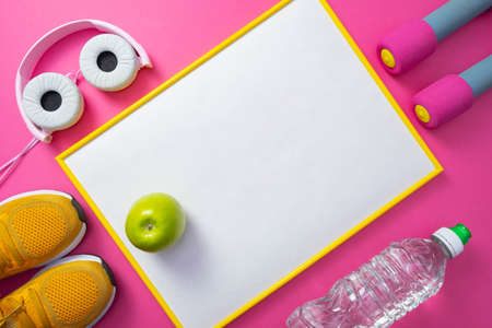 yellow sneakers and pink dumbbells, bottle of water, yellow frame with white background with green apple, headphones general pink backgroundの写真素材