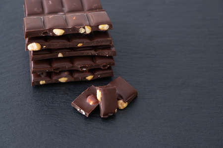 dark chocolate bars with hazelnuts lie on black backgroundの写真素材