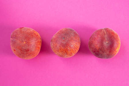 three ripe peaches lie on a pink background, close-upの写真素材