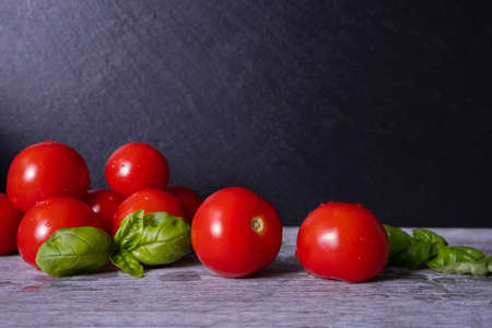 washed ripe tomatoes and basil leaves, on black background, close-upの写真素材