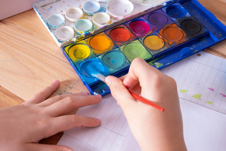 Children's hands hold a brush and interfere with the blue paint, close-upの写真素材