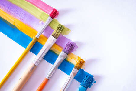 five brushes lie on a white canvas with colored lines drawn, close-upの写真素材