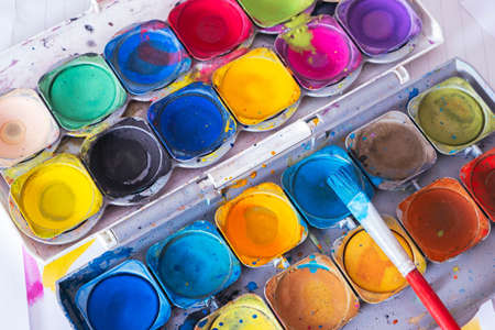open old palette of brightly colored paints with a brush, close-upの写真素材