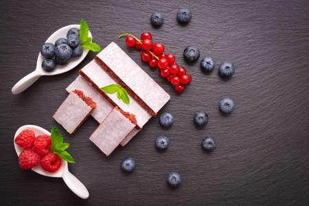 useful berry sweets - a ripe sprig of currants, raspberries and blueberries, mint leaves on a black backgroundの写真素材