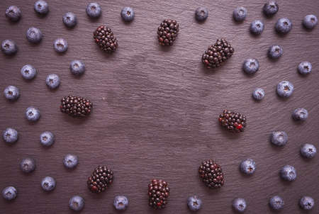 blackberries and blueberries, lie in a circle, on a black backgroundの写真素材