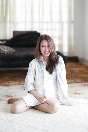 Beautiful asian woman smiling happily sitting among morning sunshineの写真素材