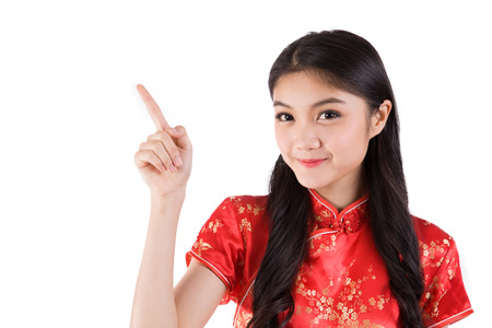Chinese girl in traditional Chinese cheongsam pointing at blank space, isolated on white backgroundの写真素材