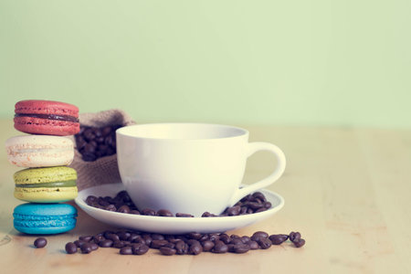Macaroons on a wooden table with cup of coffee- vintage style effect pictureの写真素材