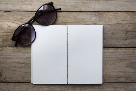 Blank diary and glasses on wood backgroundの写真素材