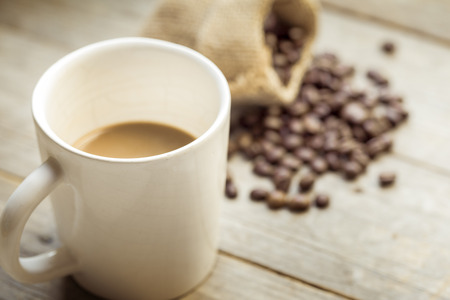 Coffee cup and coffee beans on old wooden backgroundの写真素材