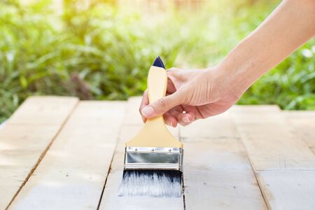 hand worker holding brush painting white on wood textureの写真素材