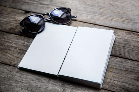 A book with glasses on wood table background