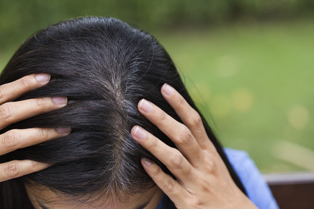 Young woman shows her gray hair roots