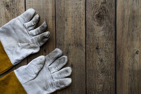 old dirty leather work gloves on wood backgroundの写真素材