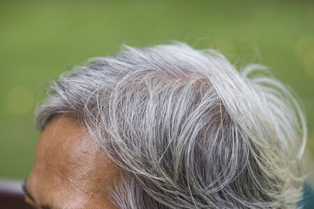 old woman shows her gray hair rootsの写真素材