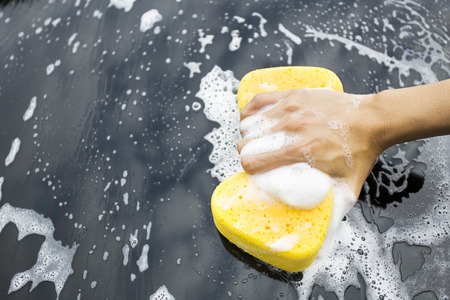 hand hold sponge over the car for washingの写真素材