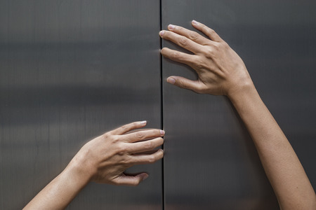 woman hands try to stop doors of the closed elevator