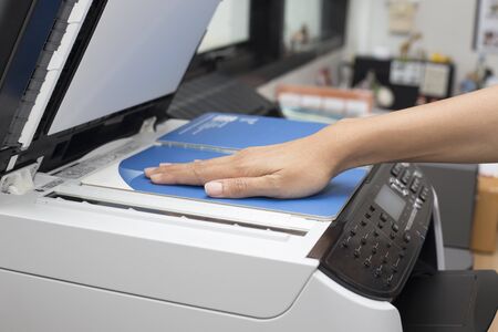 woman hands putting a sheet of paper into a copying device