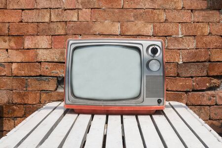Analog television on table with brick wallの写真素材