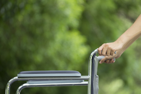 Empty wheelchair pushed by nurse's handsの写真素材