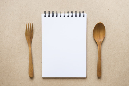 close up notebook, spoon and fork on brown paper backgroundの写真素材