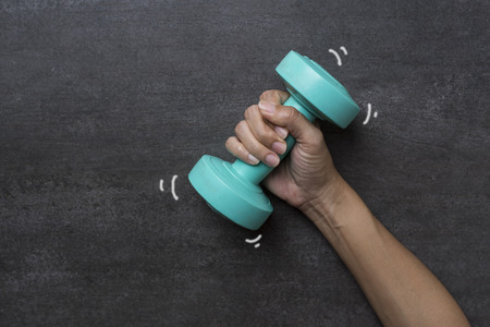 woman hand holding green dumbbell on black backgroundの写真素材