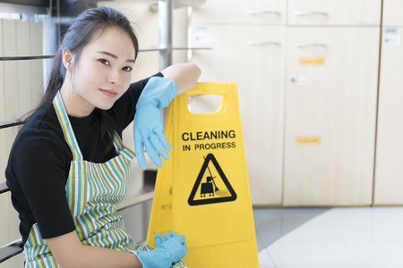Housekeeping or maid taking a break while working, leaning a cleaning sign boardの写真素材