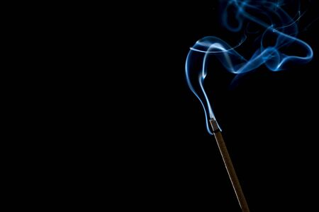 Incense stick with smoke on black backgroundの写真素材