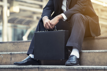 Young depressed businessman sitting on the stairsの写真素材