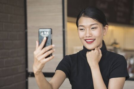portrait of asian woman take selfie using smart phone camera