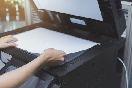 woman hands putting a sheet of paper into a copying deviceの写真素材