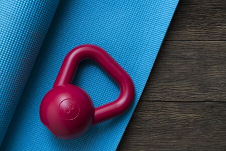 Kettlebell and yoga mat on wooden tableの写真素材